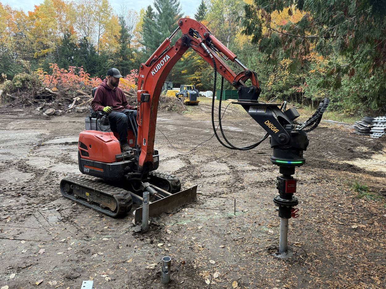 Helical pile being driven with an excavator mounted auger