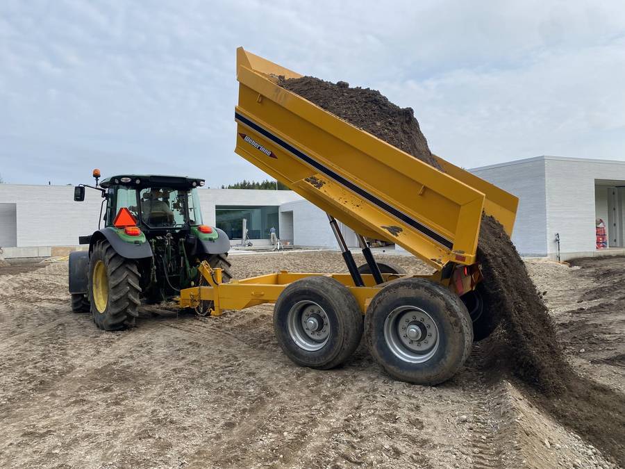 Tractor and dump trailer placing topsoil